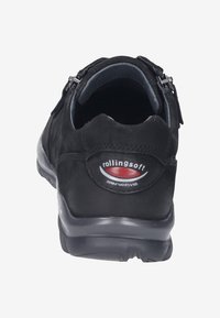 Scarpa in pelle nera con una texture morbida in camoscio, forma arrotondata, chiusura con zip sul lato e un logo sul tallone.