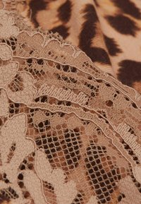 Leopardmönstrad tyg i kombination med detaljerad beige spets, med scallopade kanter och ett nätliknande mönster, vilket skapar en lager-på-lager visuell effekt.