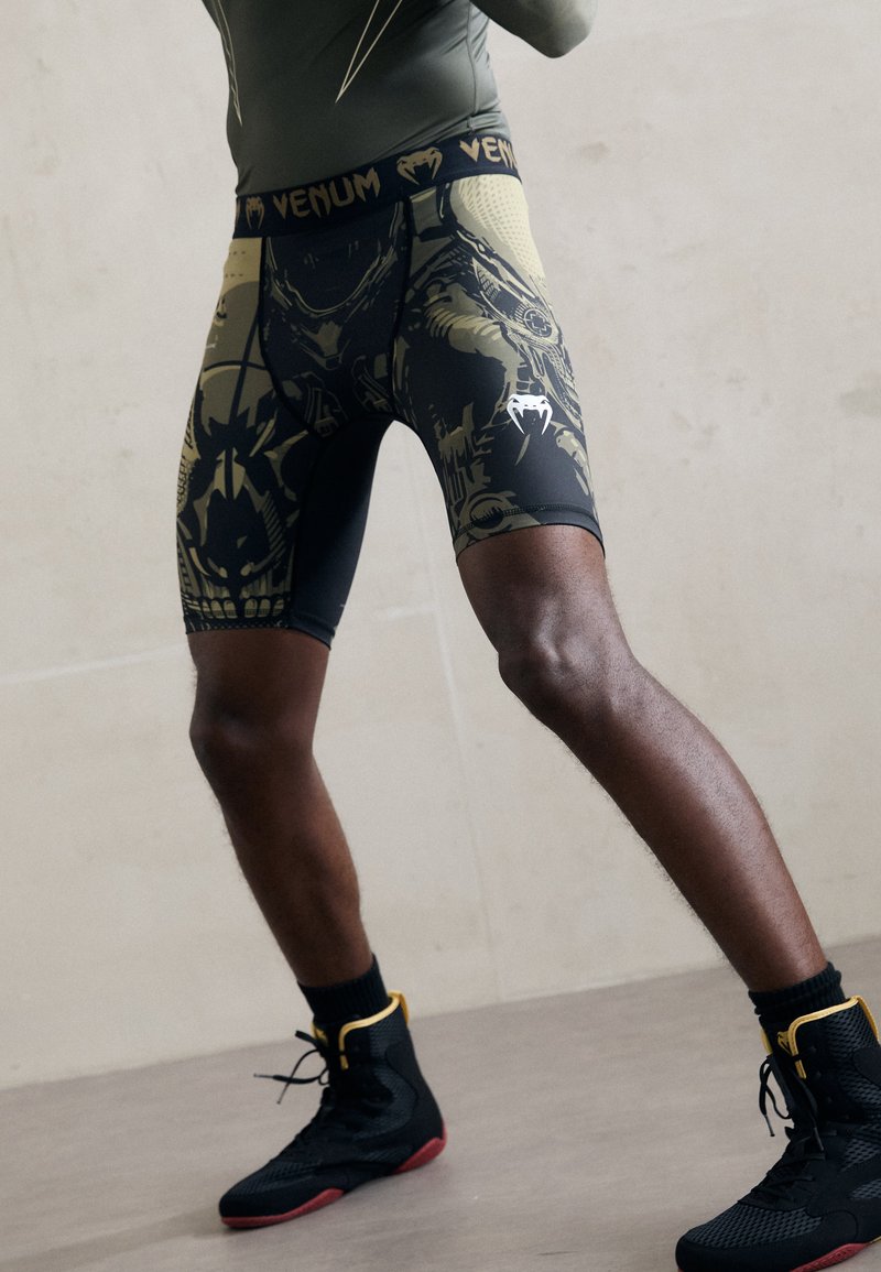 Shorts compressivi Venum in nero e oliva, con design grafici, vestibilità aderente, vita elastica e dettaglio del logo a contrasto.