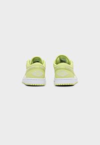 Paire de baskets basses vert citron et blanches vues de dos avec semelles intermédiaires blanches et logo décoratif sur les talons.