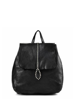 Sac à dos en cuir noir avec fermeture à rabat présentant une bande verticale de clous ronds argentés et une poignée supérieure.