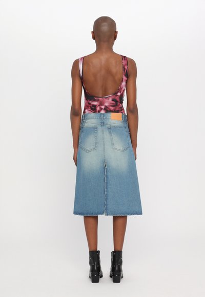 Bodysuit negro con estampado floral y espalda baja, combinado con una falda de mezclilla azul claro hasta la rodilla y botas negras hasta el tobillo.