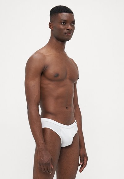 Weiße Schwimmslips aus glattem Material, mit passgenauer Form, tief sitzendem Bund und minimalistischem Nähdetails.