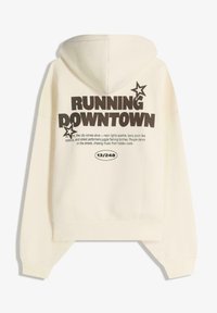 Svetlo krémová mikina s kapucňou, ktorá zobrazuje nápis "RUNNING DOWNTOWN" v tučnom čiernom písme, s individuálnymi hviezdičkami a skráteným strihom s rebrovanými manžetami.