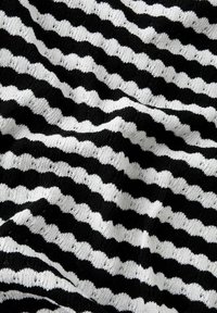 Tejido de punto en blanco y negro con un patrón de rayas onduladas. La textura es de tejido abierto con espacios visibles, creando una apariencia ligera.