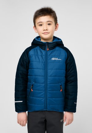 Blauwe pufferjack met donkerblauwe mouwen, voorzien van een capuchon, twee ritszakken en reflecterende accenten. Gemaakt van gewatteerd, geïsoleerd materiaal.