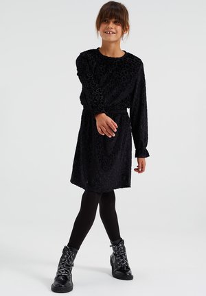 Abito nero con stampa di leopardo, maniche lunghe e vita elasticizzata, abbinato a leggins neri e stivali militari con lacci argentati.