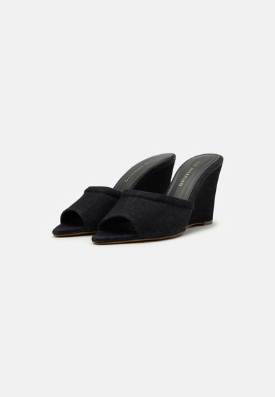 Black wedge sandals with an open toe design and textured fabric upper. Features a wide band across the foot and a sturdy wedge heel.