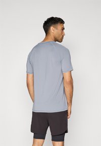 Lys blå treningst-skjorte laget av fukttransporterende stoff, med korte ermer og rund hals, samlet med svarte shorts.