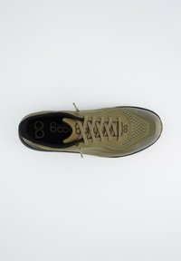 Baskets de sport en mesh vert avec une tige texturée, des accents noirs, une pointe ronde et des lacets beige clair, comportant un logo sur la semelle intérieure.