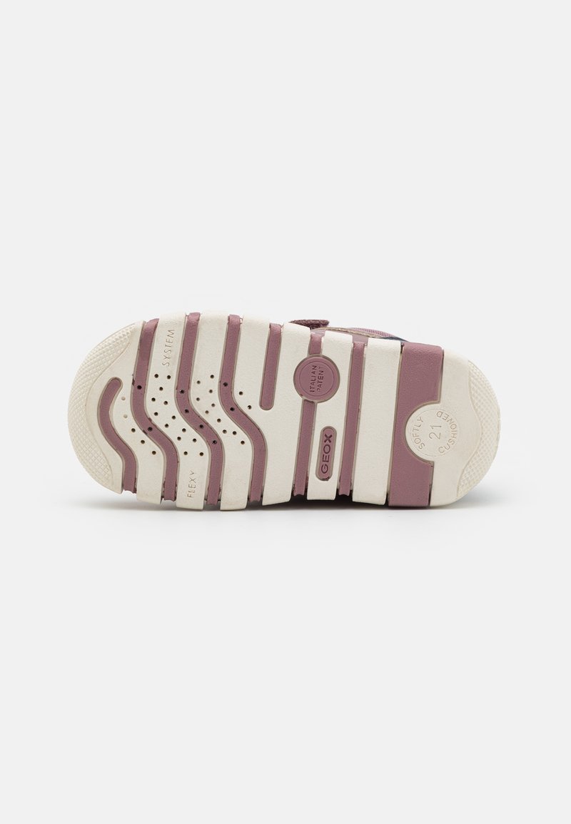 Suola di una scarpa caratterizzata da una combinazione di colori bianco e malva, con scanalature per la trazione, fori di ventilazione e dettagli di branding in rilievo.