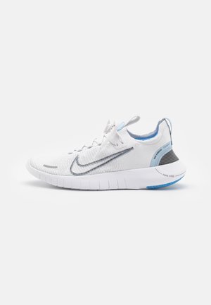 Chaussure de course Nike blanche avec empeigne en mesh, détails gris et bleus, semelle texturée et design flexible. Dispose d'un logo discret sur le côté.