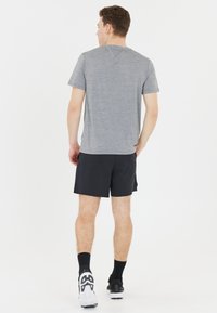 Graues T-Shirt mit kurzen Ärmeln, schwarze Sportshorts und Sneakers mit weißen Sohlen. Schlichtes Design, mittlere Passform, glatte Textur, minimale Details.