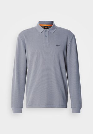 Pitkähihaisen polo-paidan vaaleanharmaa kangas, jossa on teksturoitu kuvio, kaulus ja kolme nappia. Paidassa on pieni logo rinnassa.