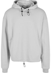 Sudadera con capucha de color gris claro hecha de tejido suave. Presenta un cierre de cordón, puños acanalados y un dobladillo corto con un ajuste regulable.