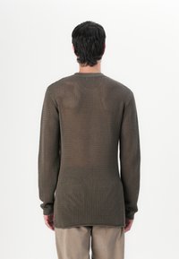 Pulover tricotat cu mânecă lungă, de culoare verde măsliniu, cu un model texturat, de tip plasă deschisă. Guler tip crew, mâneci ajustate și un tiv drept la talie.