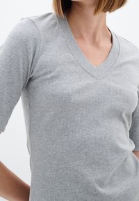 Szary prążkowany top z dekoltem w serek i krótkimi rękawami, charakteryzujący się teksturowanym materiałem i subtelnymi pionowymi liniami, ściśle przylegający do ciała.