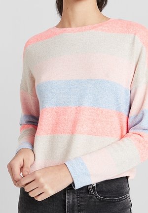 Pruhovaný svetr z měkké tkaniny má světle růžové, modré a korálové pruhy. Kulatý výstřih a dlouhé rukávy, kombinován s tmavými džíny.