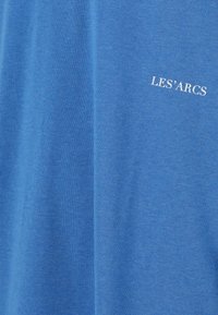 Blå bomulds t-shirt med blød tekstur, med et hvidt trykt logo "LES'ARCS" placeret på venstre frontside.