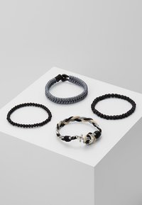 Fire armbånd: et flettet design i sort, grå og beige, et grå vævet bånd, to sorte perlearmbånd, et rundt og et tekstureret.