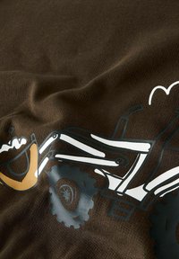 Illustrazione di un veicolo fuoristrada con pneumatici grandi e sospensione sollevata su sfondo di tessuto marrone.