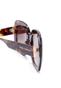 schildpadkleurige zonnebril met een chunky montuur, gradient lenzen, gouden accenten op de pootjes en merkinformatie aan de zijkant.