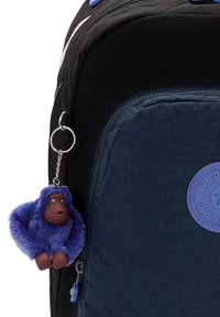 Zaino nero e blu con un esterno testurizzato, dotato di un portachiavi a forma di scimmia blu e un patch circolare blu. Scomparto principale con zip.