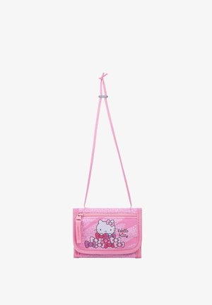 Piccolo portafoglio Hello Kitty rosa con motivi a fiocco e tracolla, appeso contro uno sfondo bianco.