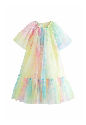 Enfant portant une robe en tulle arc-en-ciel pastel avec des manches bouffantes et des sandales blanches, debout sur un fond beige.
