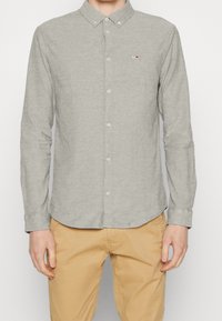 Szara koszula na długi rękaw z guzikami, o miękkiej fakturze, z kołnierzykiem zapinanym na guziki i małym, firmowym logo na piersi.