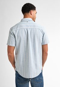 Korte mouwen overhemd in lichtblauw met witte verticale strepen. Voorzien van een button-down kraag en een gebogen zoom, gemaakt van een lichte stof.