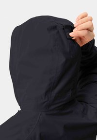 Giacca nera impermeabile con colletto alto e cappuccio regolabile. Presenta una tracolla in velcro e una texture liscia.