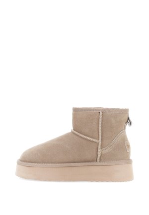 Beige ruskindsankelstøvle med rund tå, minimal syning, trækflig bagpå og flad gummisål. Glat, blød tekstur.