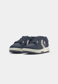 Dark blue sneakers with a smooth fabric finish, contrasting light gray accents, lace-up design, and a white sole with branding detail.