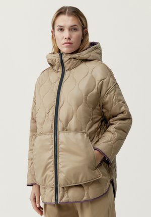 Giacca imbottita trapuntata beige con cappuccio, dotata di chiusura a zip, due tasche frontali e rifiniture viola lungo i polsini e l'orlo.