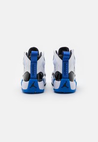 Białe sneakersy typu high-top z błyszczącymi czarnymi akcentami i niebieskimi detalami. Posiadają wyściółkę w okolicy kostki oraz charakterystyczny trapezoidalny design obcasa.