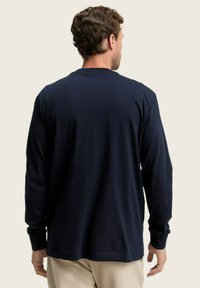 Camiseta de manga larga color navy, hecha de una tela suave, con cuello redondo, dobladillo recto y corte relajado. Sin logos ni patrones visibles.