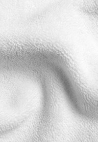 Vit frottétyg som visar en mjuk yta med distinkta öglor. Materialet verkar fylligt och är något skrynkligt, vilket indikerar flexibilitet.