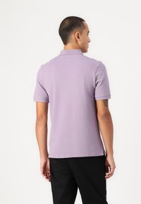 Kortermet polo skjorte i lavendel bomull, med klassisk krage og sidesplitter. Bakdelen har et enkelt design med en avslappet passform.