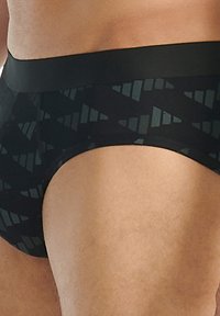 Mustat alushousut, jotka on valmistettu sileästä kankaasta ja joissa on tumma sävyinen geometrinen kuvio. Elastinen vyötärölaatikko tiiviin istuvuuden takaamiseksi.