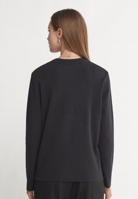 Zwarte langslijfs T-shirt van katoen, met een ronde hals, rechte snit en minimalistisch ontwerp. Soepele textuur.