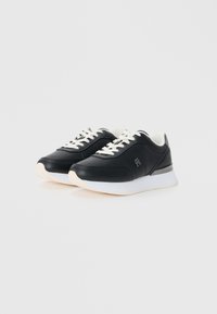 Black sneakers with a smooth leather upper, white laces, padded collar, and textured rubber outsole; features a subtle logo on the side.