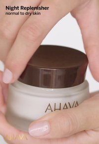 AHAVA Nachtauffüller in einem frosted Glasbehälter mit einem dunkelbraunen Deckel. Der Behälter hat eine glatte Textur und verfügt über erhabene Schriftzüge.