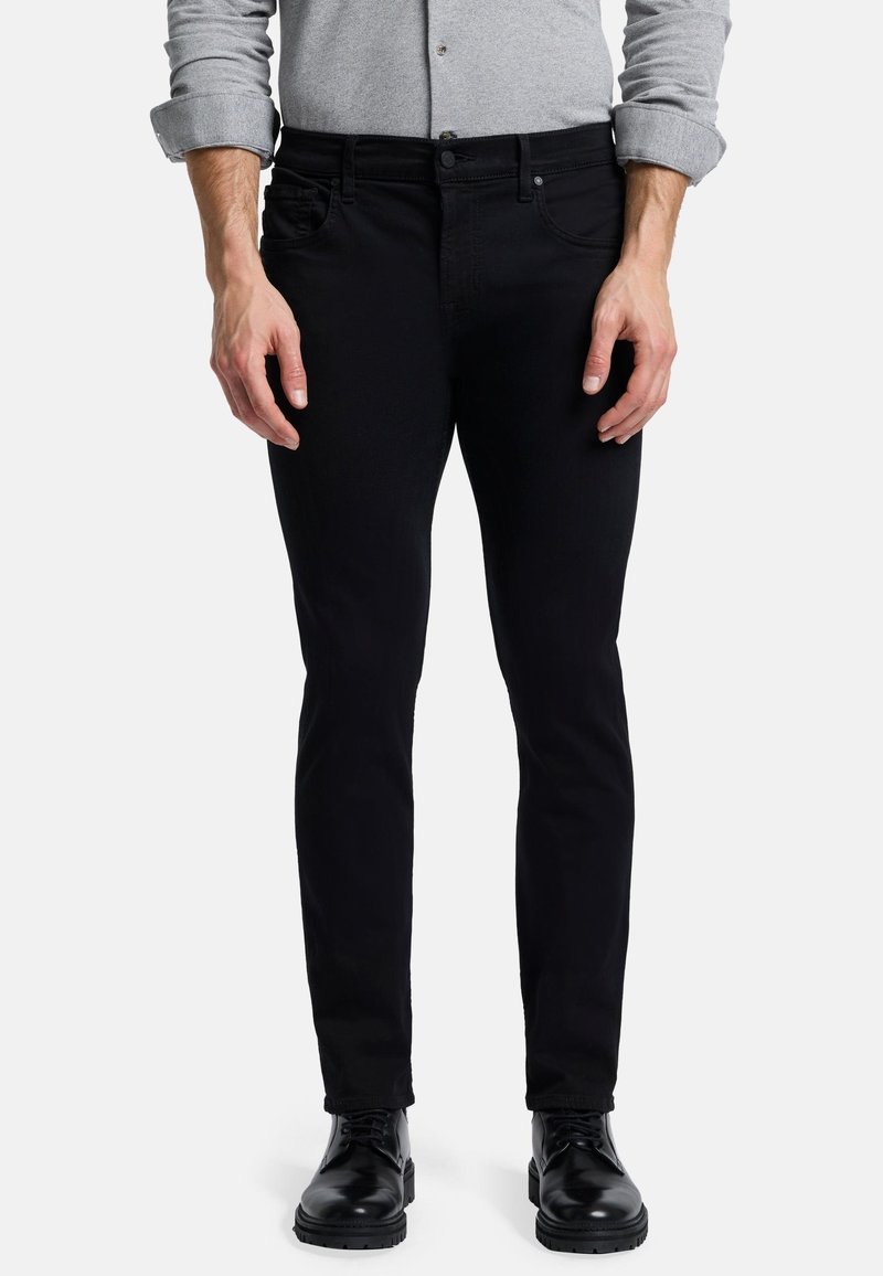 Sorte denimjeans med slim fit, fem lomme-design og en glat tekstur. Har diskret syninger og slidte sorte læderstøvler.