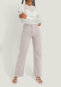 White long-sleeve blouse with lace detailing, paired with light purple wide-leg jeans featuring fringed hems and traditional five-pocket design.