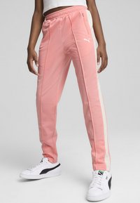 Roza poliester športne hlače z belimi stranskimi črtami, elastičnim pasom in žepi na zadrgo. V kombinaciji z belimi supergami, ki imajo črno akcentacijo.