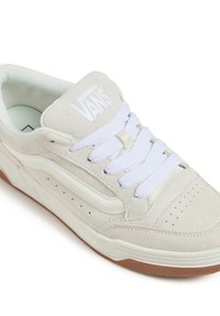Baskets en suède blanches avec lacets blancs, un logo blanc sur la languette et une semelle en caoutchouc coloris gomme. Présente des détails perforés et un design élancé.