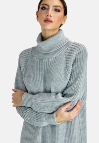 Heller grauer Rollkragenpullover aus strukturiertem Strickstoff, mit gerippten Akzenten an Kragen und Bündchen, im lässigen Schnitt.