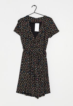 Zwarte jurk met een geometrisch patroon van zeshoeken en gekleurde bloemen in roze, blauw en wit. V-hals en korte mouwen.