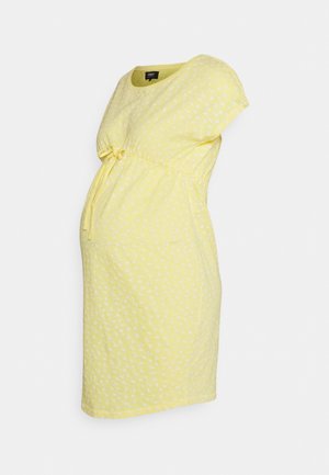 Gelbes Schwangerschaftskleid mit kurzen Ärmeln, weißem Blumenmuster und verstellbarem Taillengürtel vor einfarbigem Hintergrund.